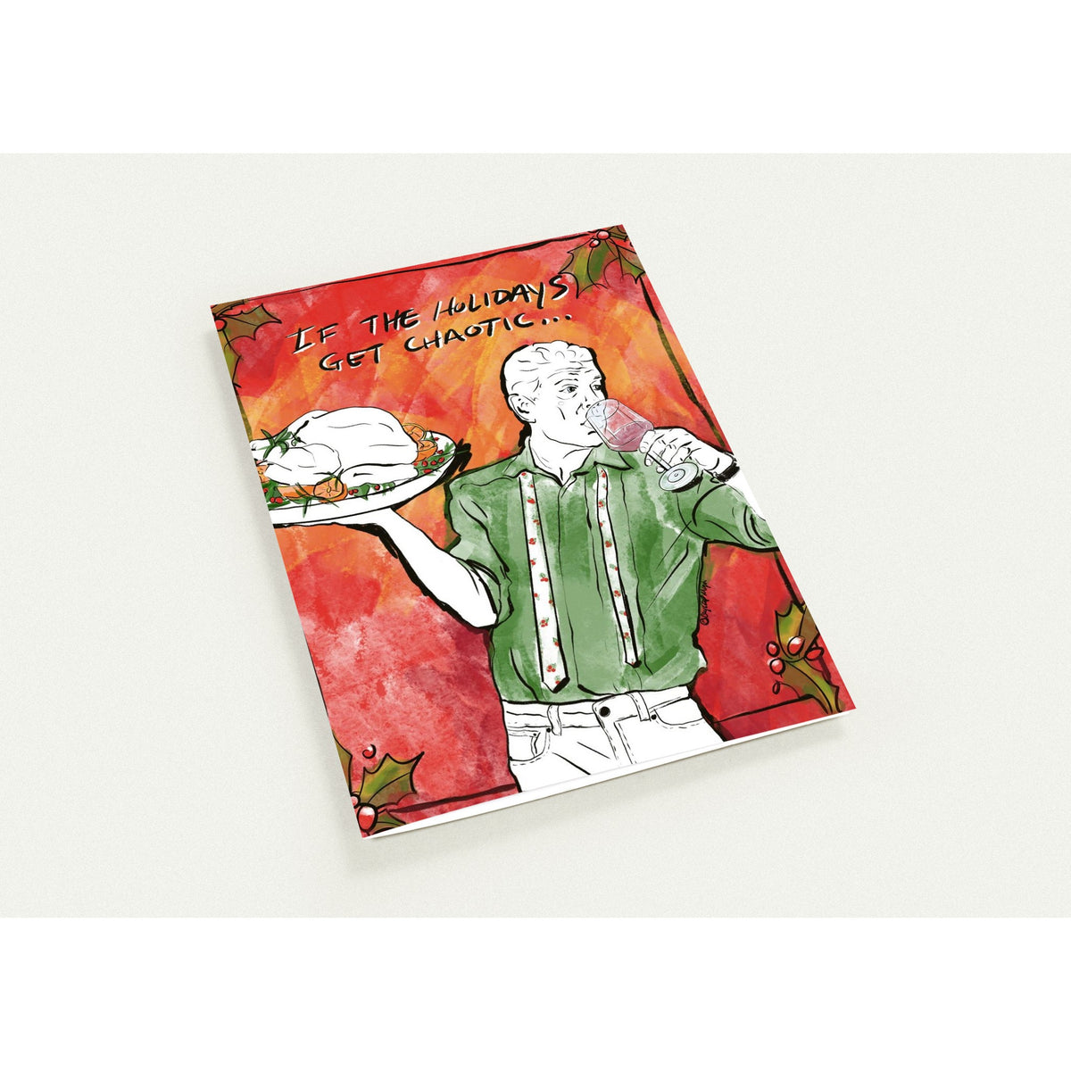 Anthony Bourdain holiday greeting card featuring Bourdain holding a turkey platter and wine glass, wearing a green holiday shirt and berry-patterned tie, with the phrase "If the holidays get chaotic..." surrounded by festive holly.